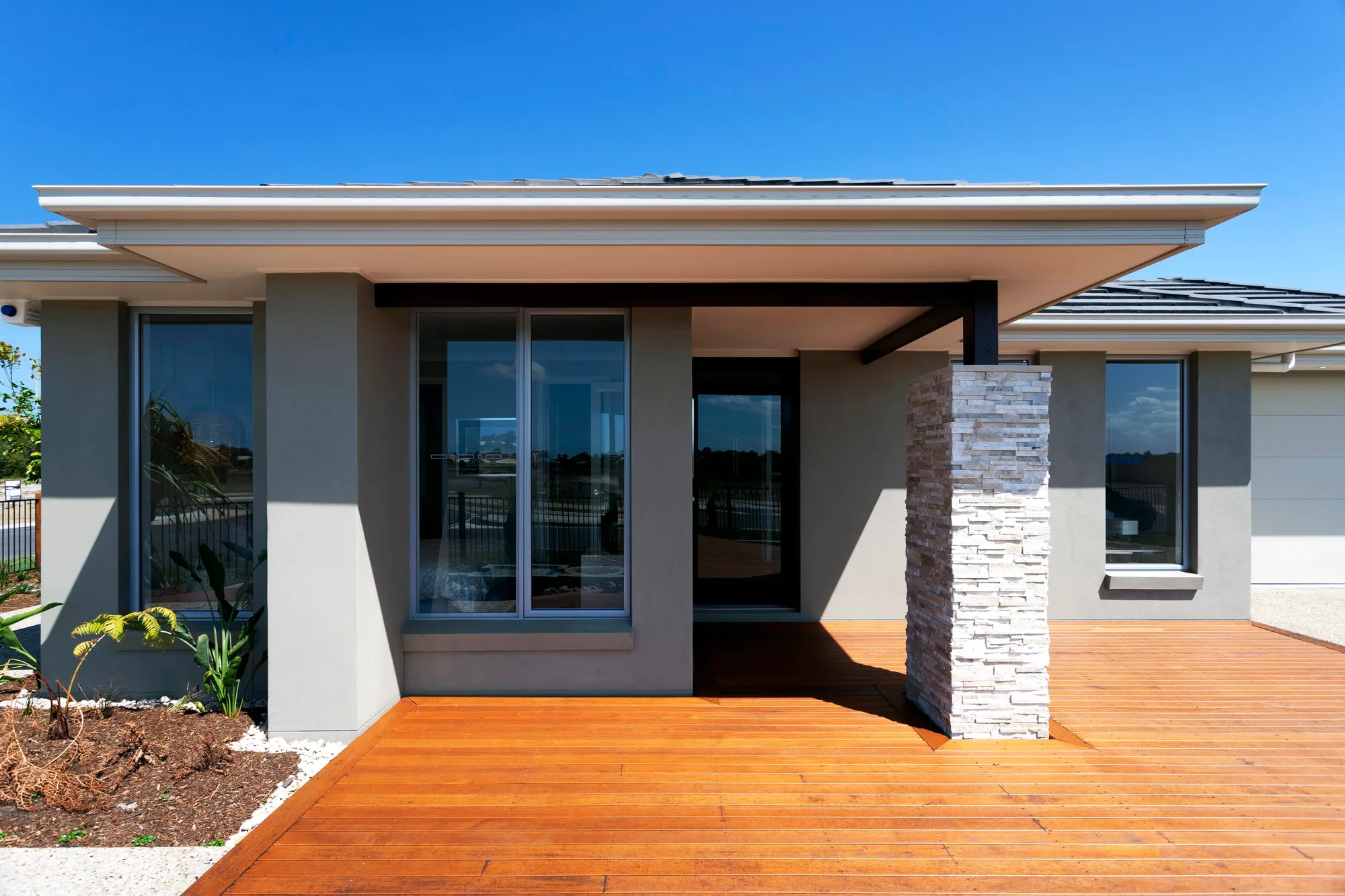 A sunlit timber deck at a modern home's entrance