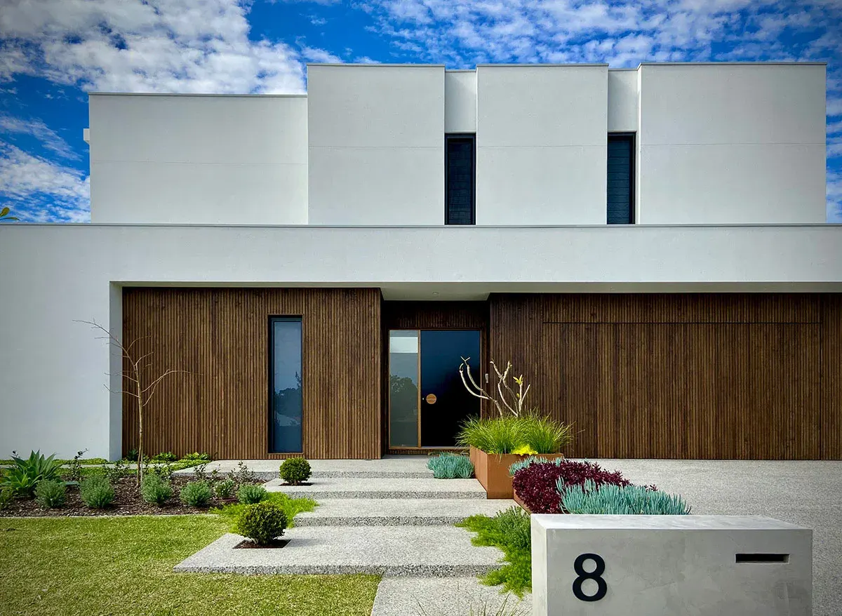 A newly landscaped front garden with a paved path, garden beds and lawn