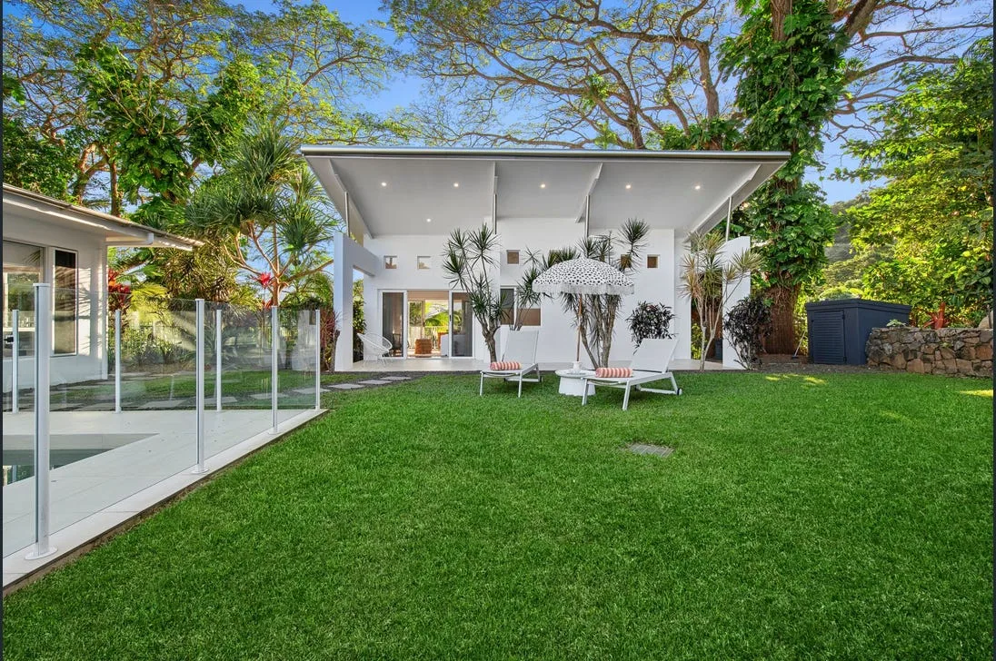 A backyard pool edge with lush lawn and outdoor lounge furniture