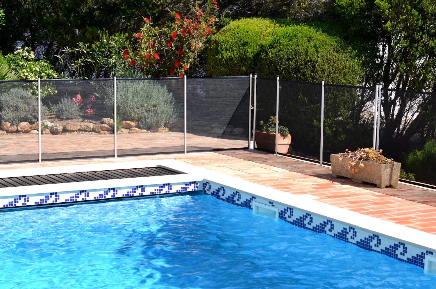 A pool edge with tiled mosaic border and surrounding paved courtyard