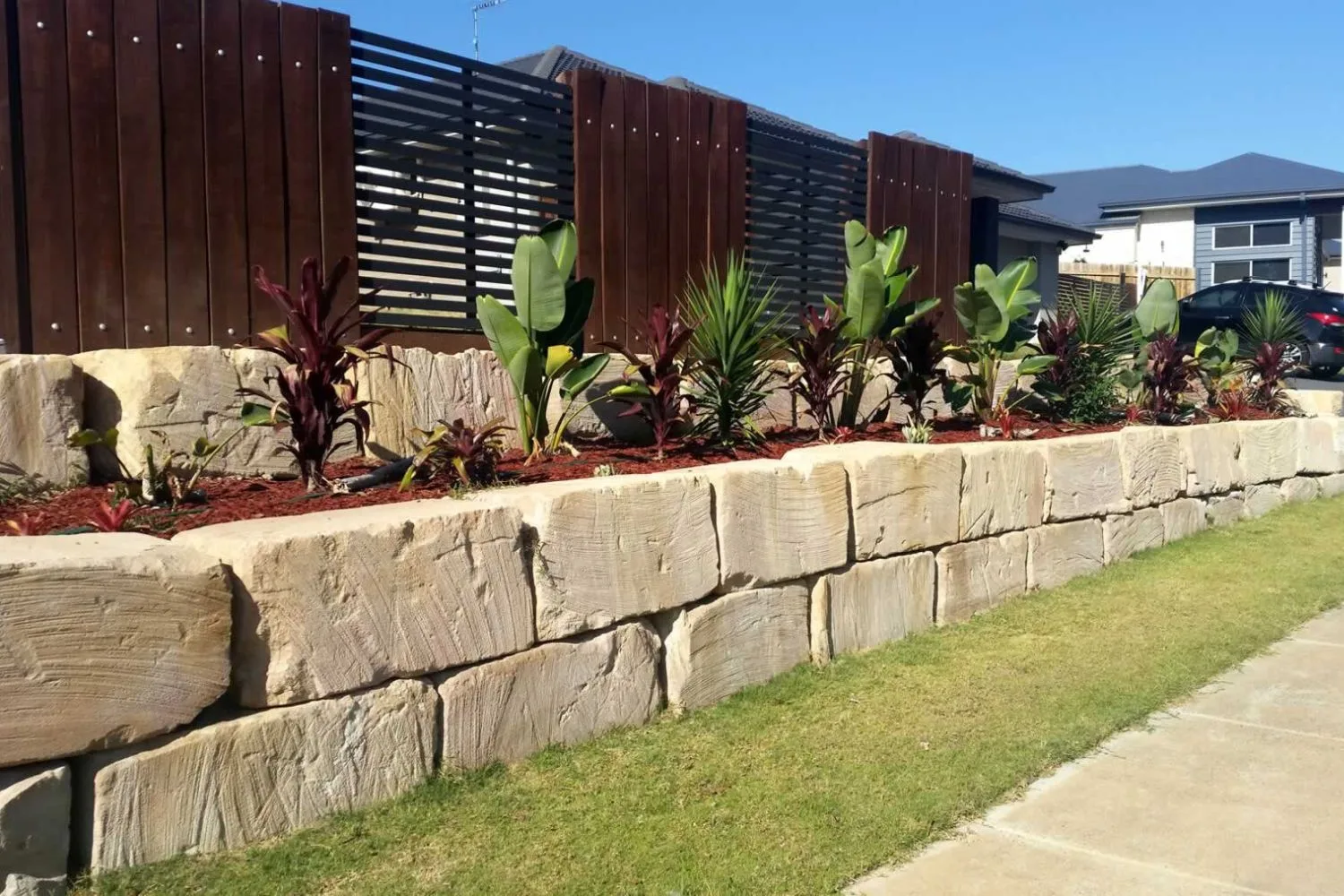 A natural sandstone block retaining wall along a garden bed
