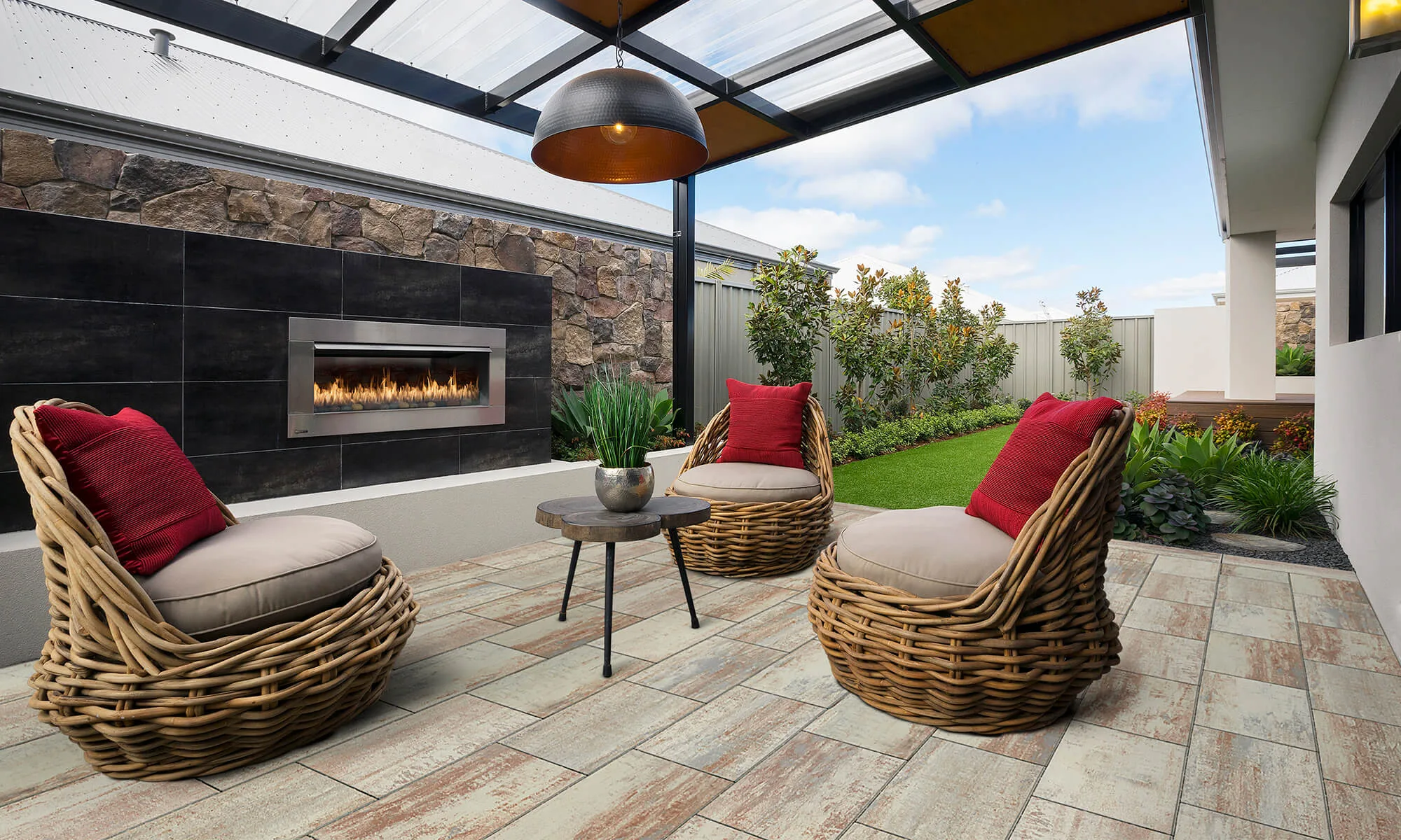 A covered outdoor patio with a stone feature wall, gas fireplace and wicker lounge chairs