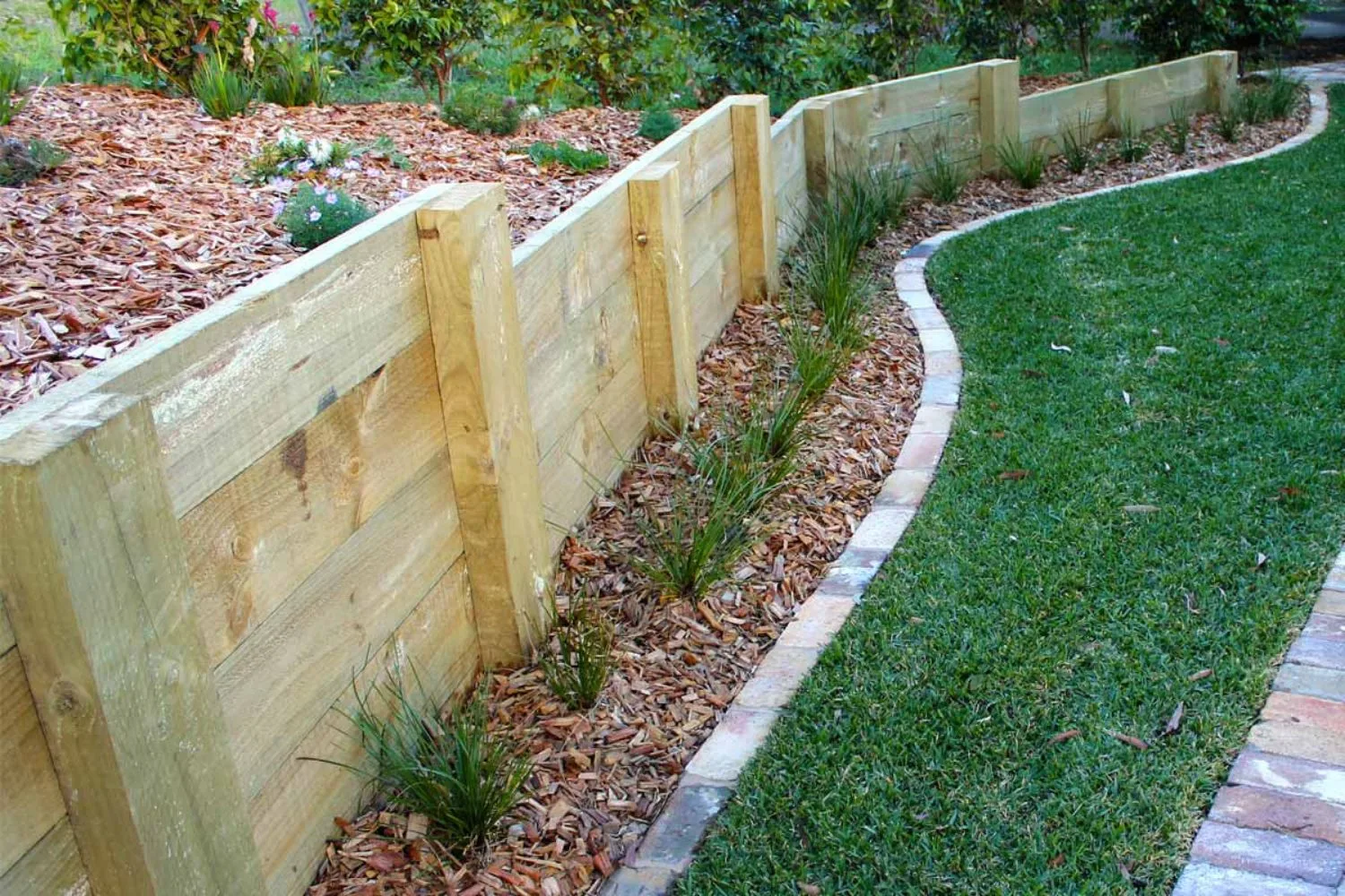 A timber sleeper retaining wall along a curved lawn edge
